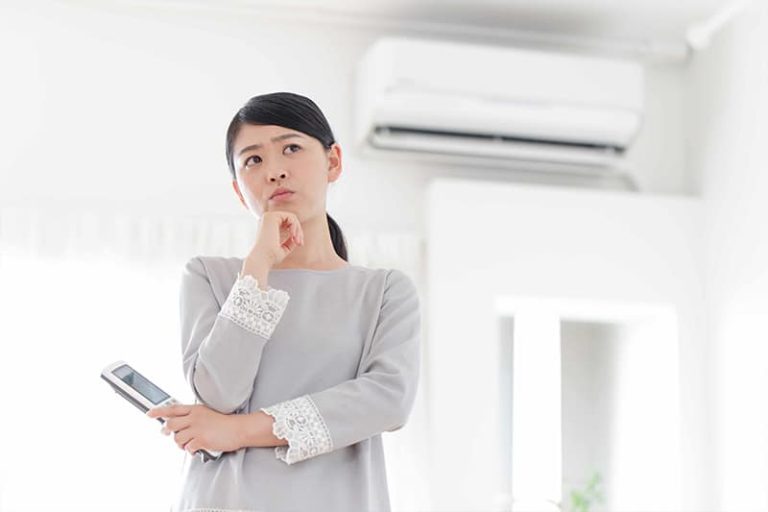 young woman holding air conditioner remote control